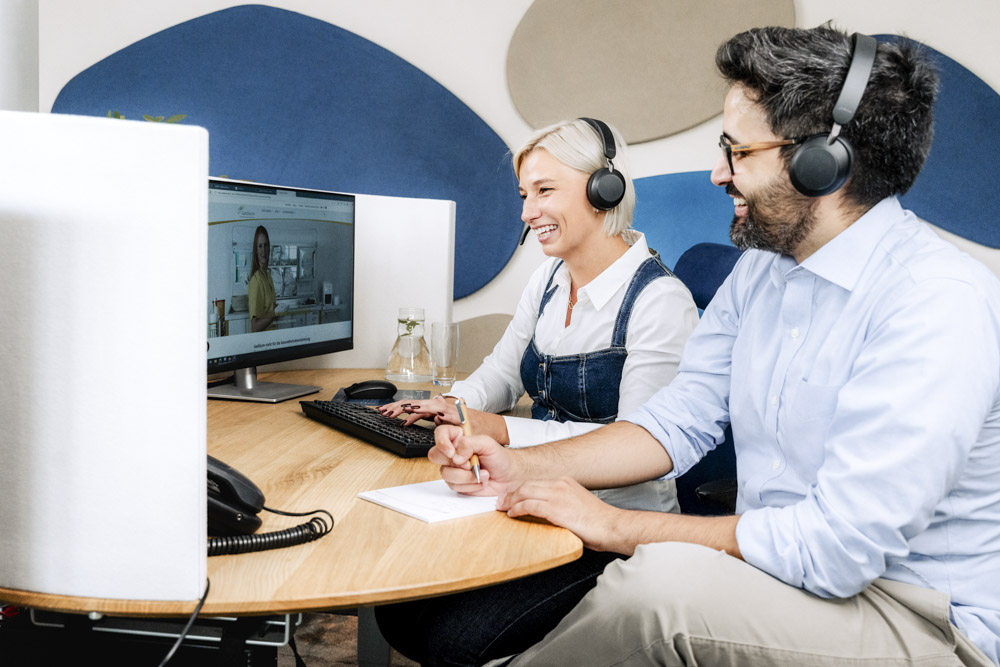 Job bei Gedikom - Freundlich lächelnde Mitarbeitende der Gedikom im Servicecenter am Arbeitsplatz